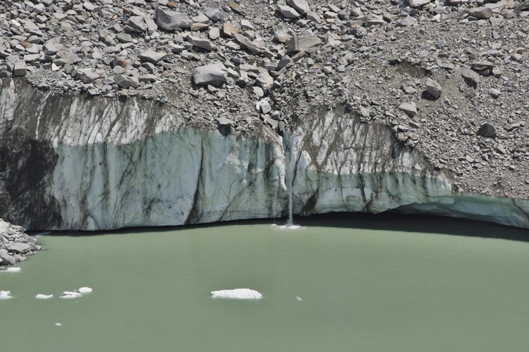 waterfall from under the rocks, over the ice, and into the water