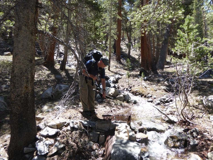 Blackfoot clearing debris from grate over pipeline intake.