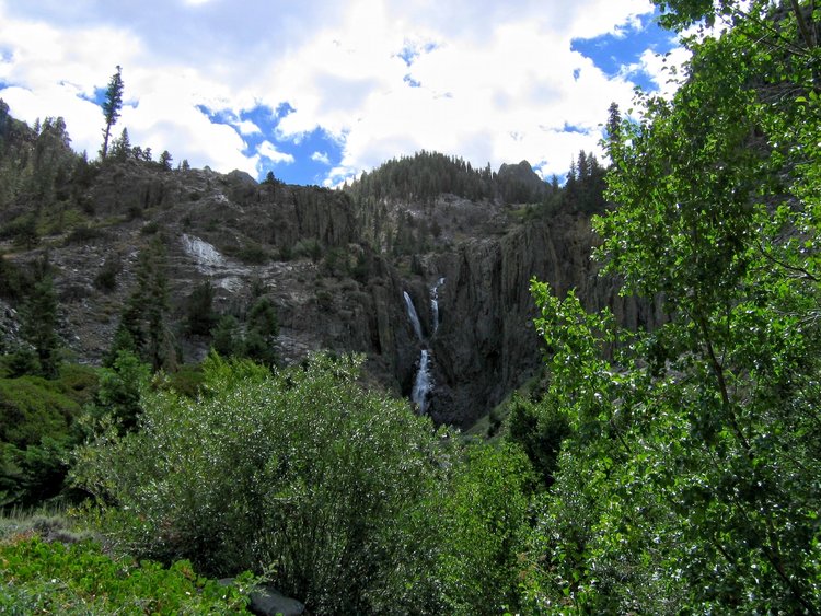 A wide view from below Triple Falls; a use trail is to the left of the falls.