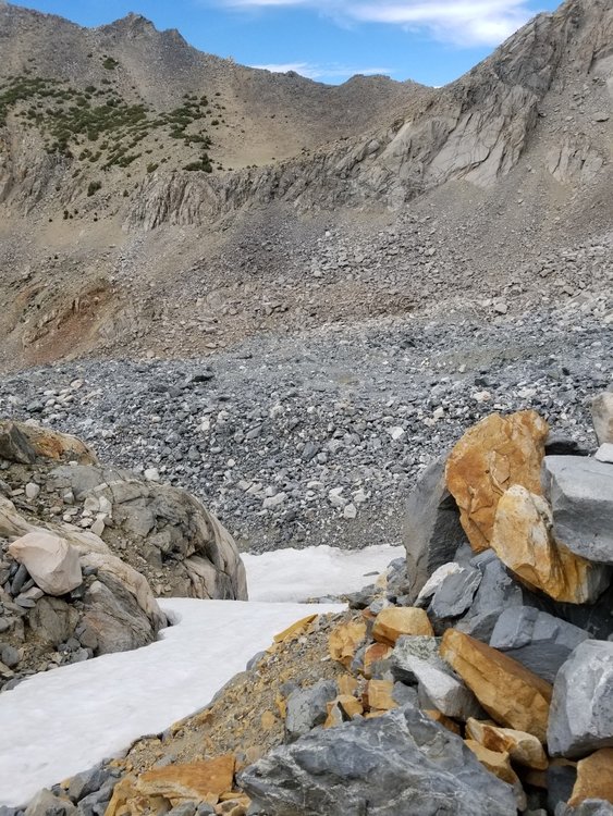 The upper most (and crossable) start of the steep snow field, whose angle steepens significantly at the mid-photo drop off.  Left of this photo are impassable rock walls.  Right is the loose scree that lets one surpass the steep snow.  Around the sharp corner to the left at the bottom of the snow is the route to Dragon Lake.