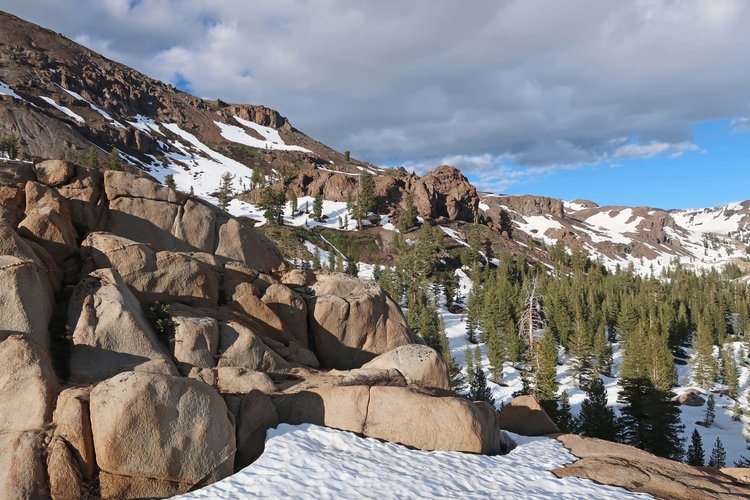 Snow has melted more on the sunny slope with dark rock
