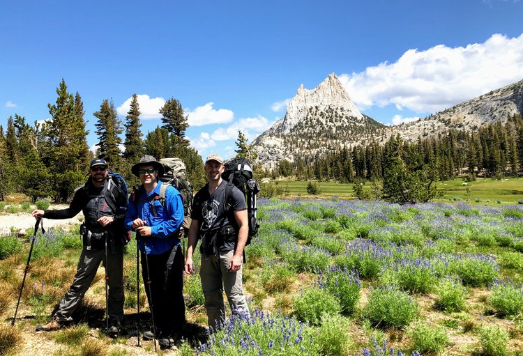 The crew and lupine next to the JMT, Cathedral in back.